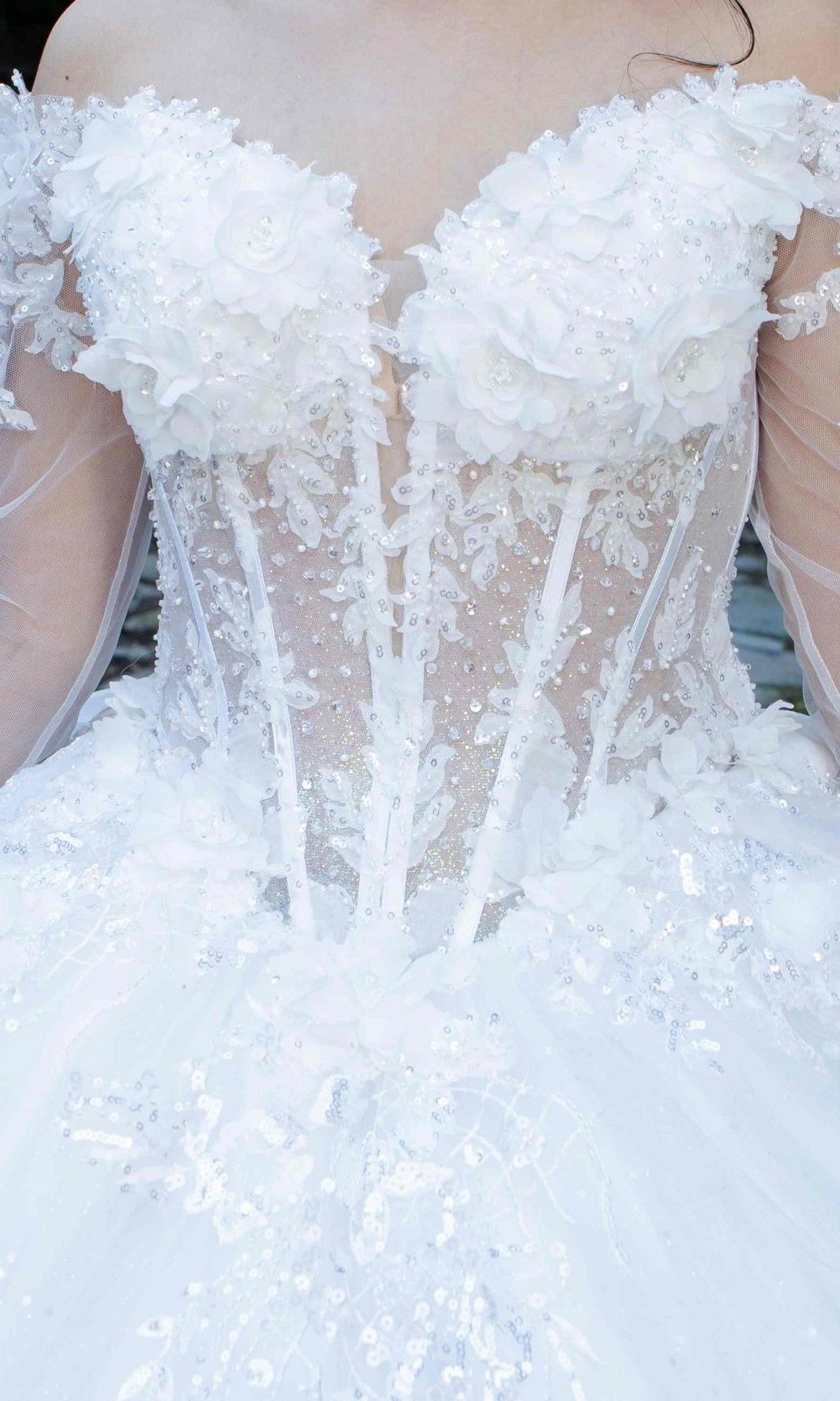 Close-up of the Cinderella Couture 8325J, a long formal white ball gown featuring an off-the-shoulder design with floral appliqués, sequins, glitter tulle, and a sheer corset bodice.